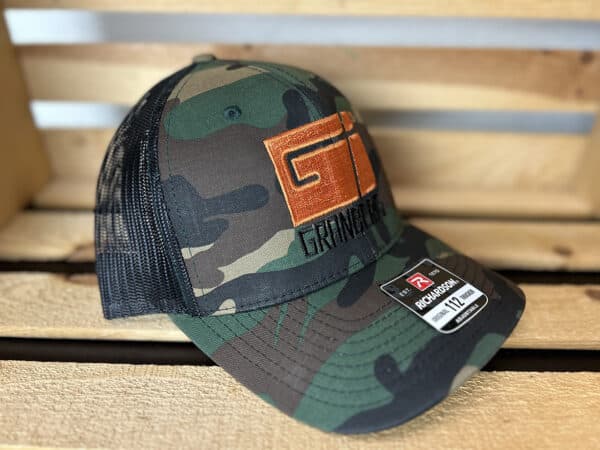 A Granberg Snap Back Trucker Mesh Hat (Camo/Black) is displayed on a wooden chair.