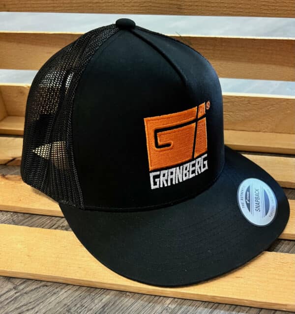 A Granberg Snap Back Mesh Hat (Black) is displayed on a wooden chair.